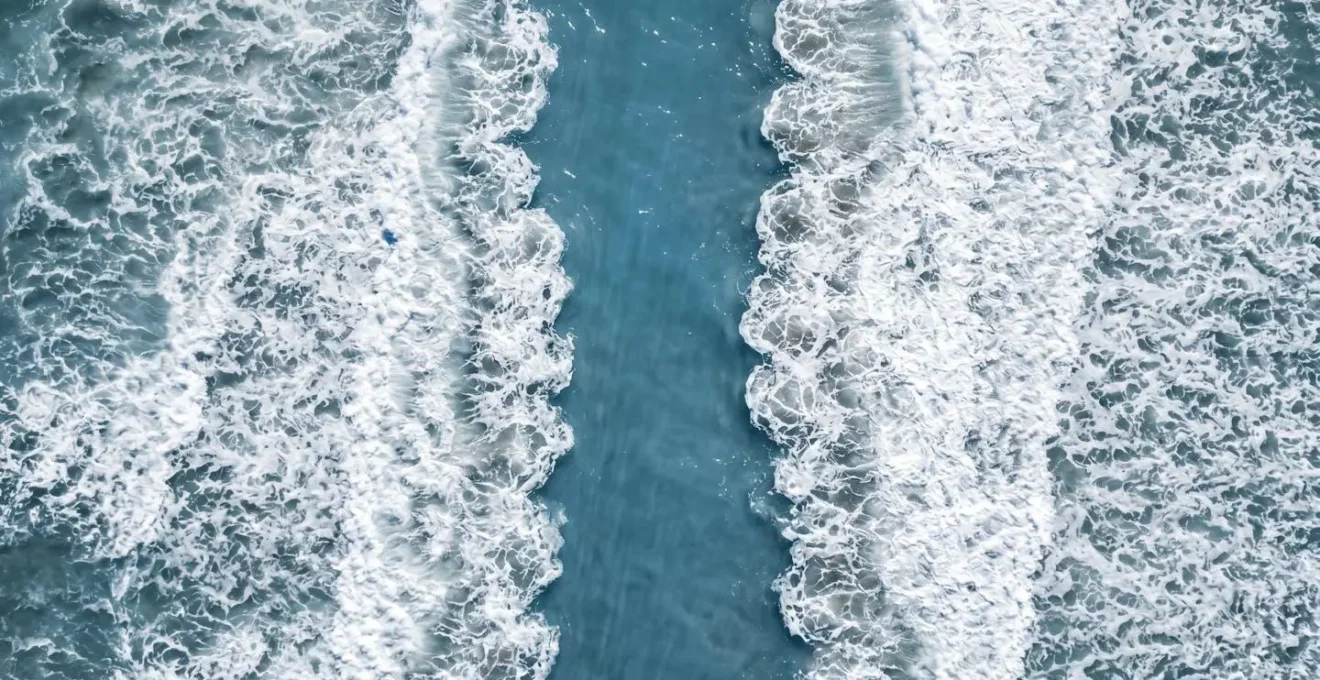 Aerial view of ocean showing contrasting water patterns with a calm, deceptive channel between rough waves